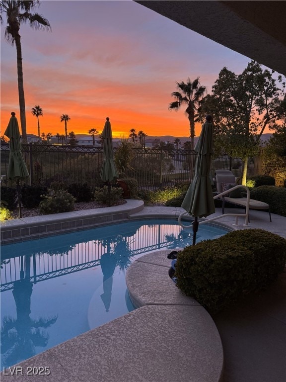 pool at dusk featuring a patio, fence, and a fenced in pool