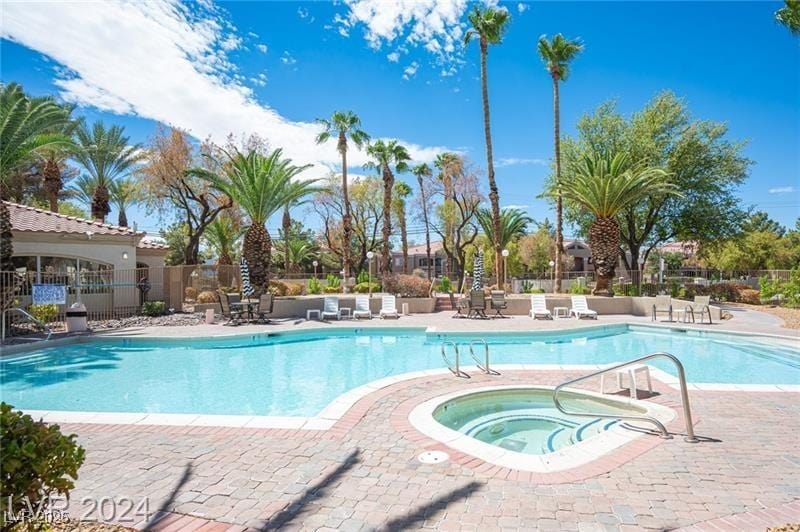 community pool with a patio area, a community hot tub, and fence