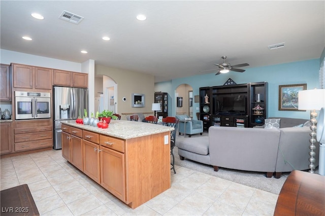 kitchen featuring stainless steel appliances, arched walkways, visible vents, and open floor plan