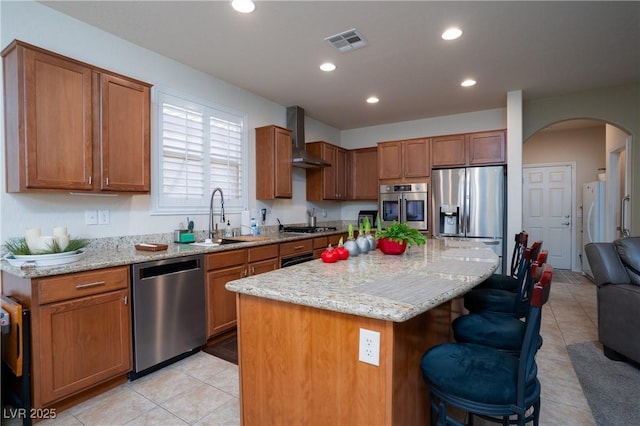 609 Viale Machiavelli Ln, Henderson, NV 89011 - kitchen featuring appliances with stainless steel finishes, a sink, wall chimney exhaust hood, arched walkways, and a kitchen bar