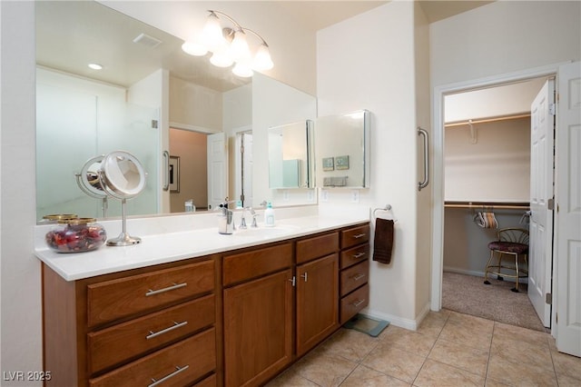 full bath featuring tile patterned flooring, a walk in closet, vanity, and baseboards