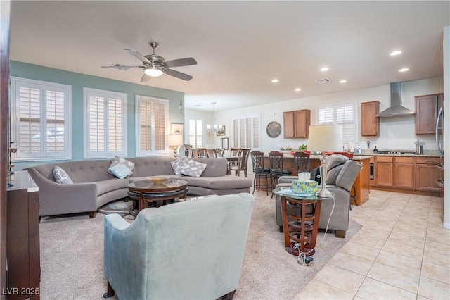 living area with ceiling fan with notable chandelier, light tile patterned flooring, recessed lighting, and visible vents