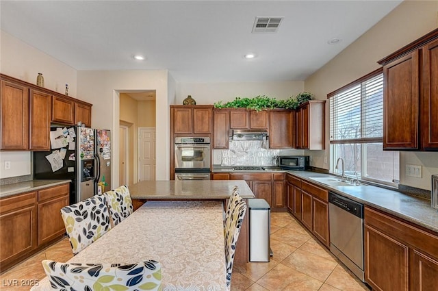 kitchen with visible vents, a sink, under cabinet range hood, stainless steel appliances, and light tile patterned flooring