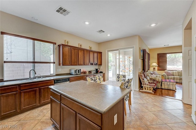 kitchen featuring light tile patterned flooring, visible vents, a center island, and a sink