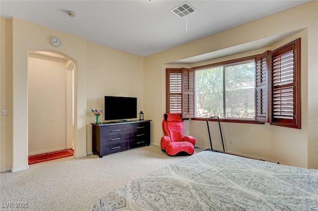 bedroom featuring arched walkways, carpet flooring, baseboards, and visible vents