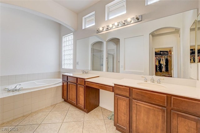 bathroom featuring a shower stall, a garden tub, double vanity, tile patterned floors, and a sink