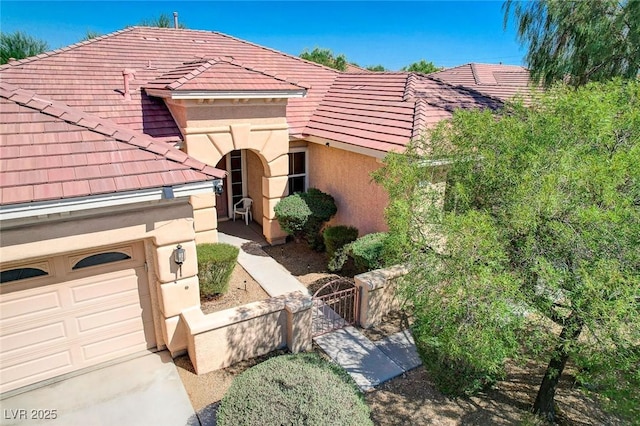 mediterranean / spanish house with a tiled roof, a garage, and stucco siding