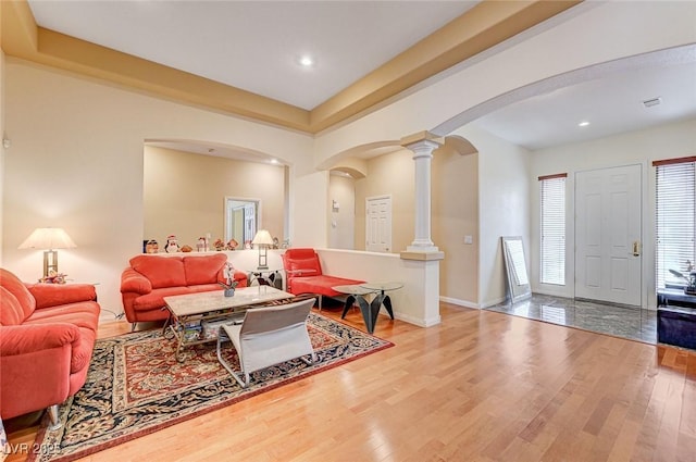 living area with wood finished floors, baseboards, ornate columns, recessed lighting, and arched walkways