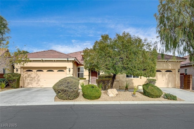 view of front facade with concrete driveway, an attached garage, a tile roof, and stucco siding