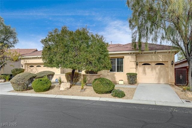 view of front of home featuring stucco siding, driveway, an attached garage, and a tile roof