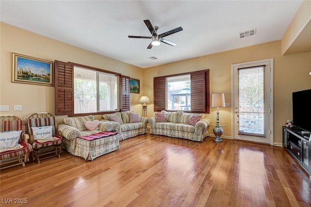 living room with visible vents, baseboards, a ceiling fan, and light wood finished floors