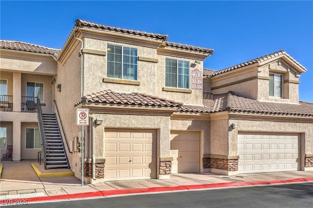 view of front of home featuring stucco siding, stone siding, stairway, a garage, and a tiled roof