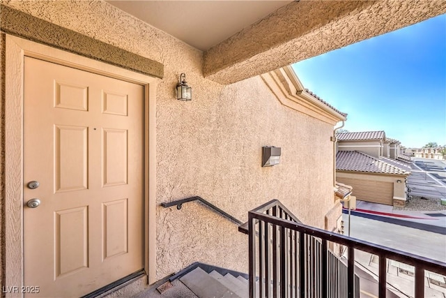 view of exterior entry with a balcony and stucco siding