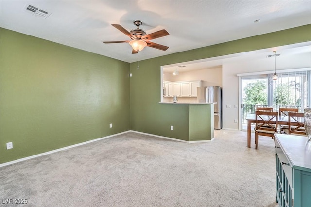 spare room with visible vents, baseboards, light colored carpet, and a ceiling fan