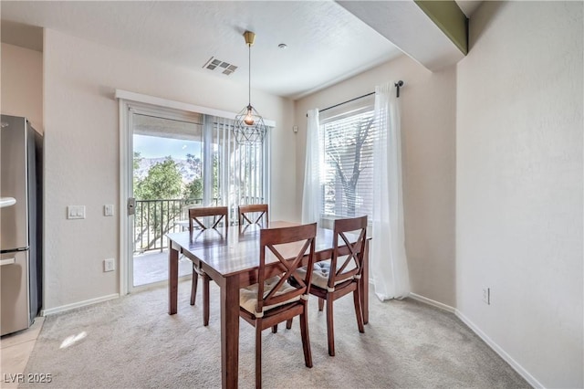 dining area with light colored carpet, visible vents, and baseboards