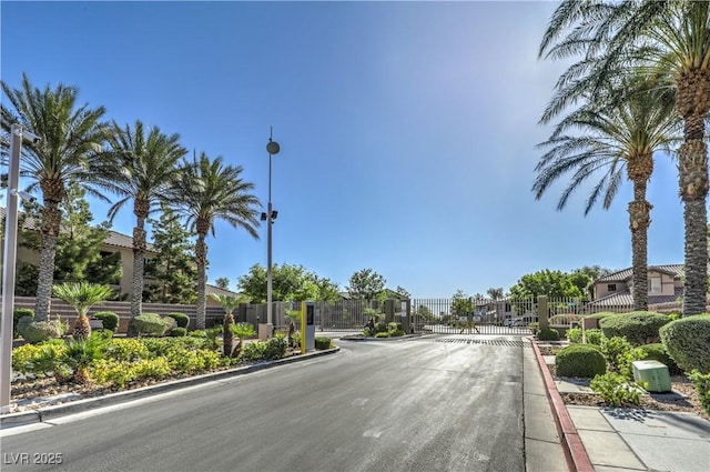 view of street featuring curbs, a gated entry, street lighting, and a gate