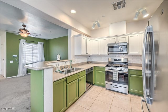 kitchen featuring visible vents, green cabinetry, a sink, stainless steel appliances, and tasteful backsplash