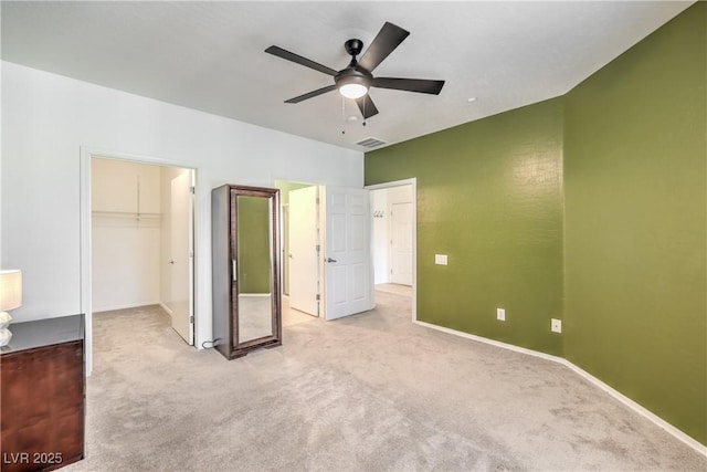 unfurnished bedroom featuring a spacious closet, baseboards, light carpet, and a closet