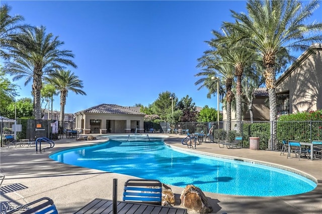 community pool with a patio and fence