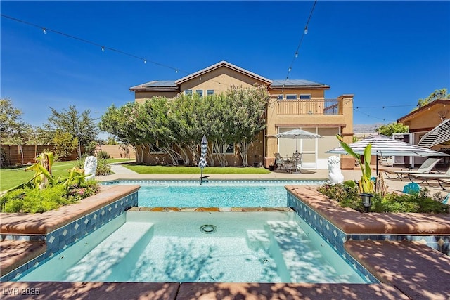 view of pool with a patio area, fence, and a pool with connected hot tub