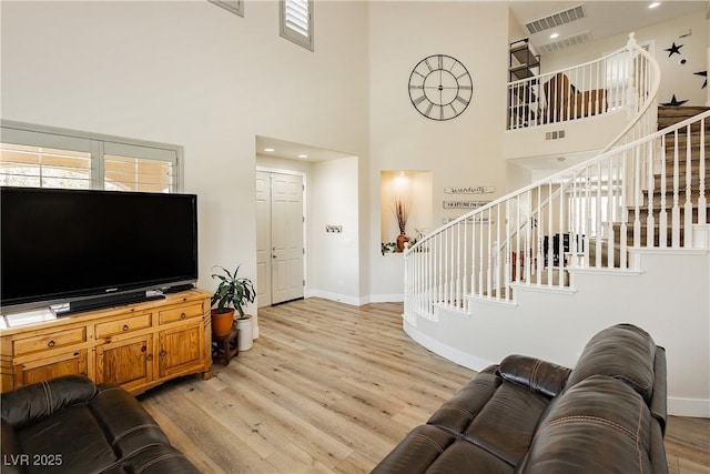 living room with visible vents, stairway, baseboards, and light wood-style floors