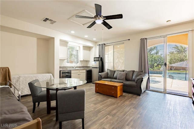 living area with visible vents, wood finished floors, and beverage cooler