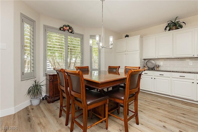 dining area with baseboards, light wood-style floors, and a chandelier