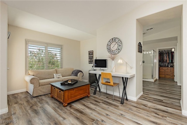 living area featuring visible vents, baseboards, and wood finished floors