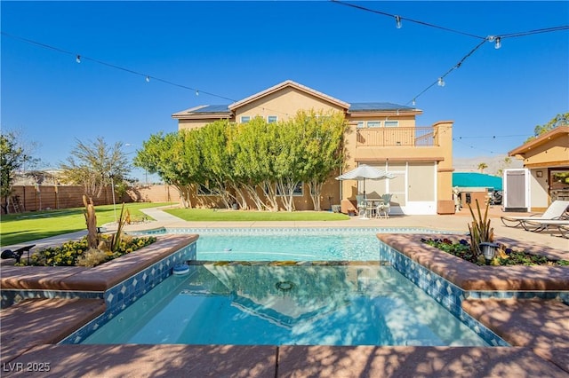 view of pool featuring a patio, a yard, a fenced backyard, and a pool with connected hot tub