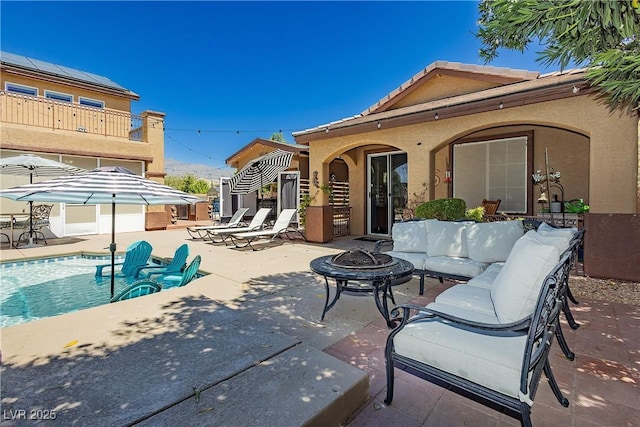 view of patio with an outdoor pool and an outdoor fire pit