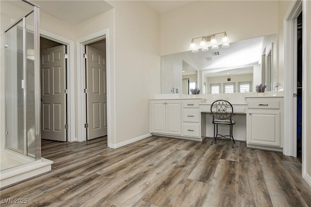 full bath with a stall shower, vanity, baseboards, and wood finished floors