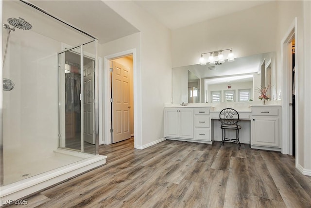 full bathroom featuring a stall shower, baseboards, wood finished floors, and vanity