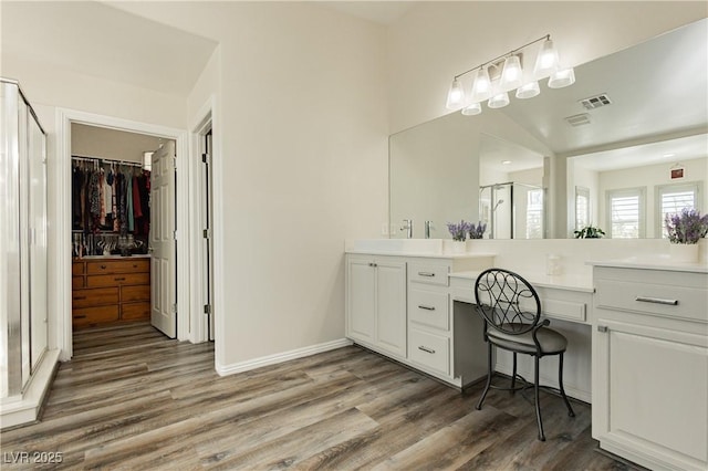 full bath with vanity, a shower stall, wood finished floors, and baseboards