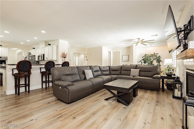 6391 Tempting Choice Ave, Las Vegas, NV 89131 - living room featuring ceiling fan, light wood-style flooring, arched walkways, recessed lighting, and a glass covered fireplace