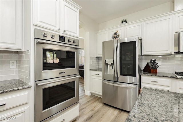 kitchen with decorative backsplash, white cabinets, and stainless steel appliances