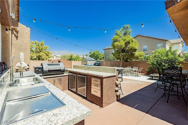 view of patio / terrace featuring outdoor dining area, an outbuilding, an outdoor kitchen, and a fenced backyard