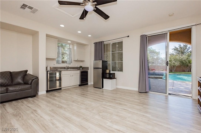 living area featuring wet bar, wine cooler, light wood-style flooring, and visible vents