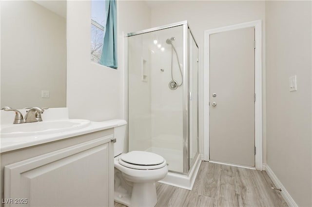 bathroom with wood finished floors, toilet, a stall shower, and vanity