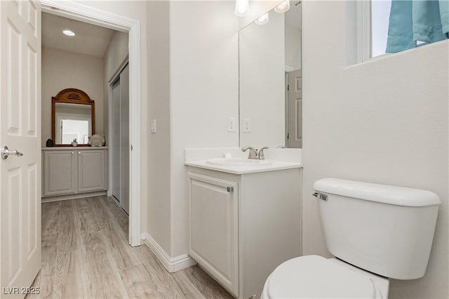 bathroom featuring toilet, vanity, baseboards, and wood finished floors