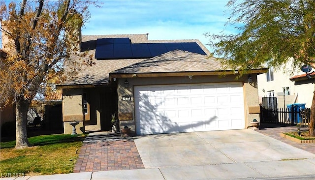 view of front of house featuring roof mounted solar panels, driveway, a shingled roof, and a garage