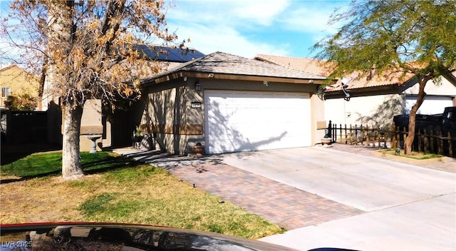 view of front of house with a garage, stucco siding, driveway, and fence