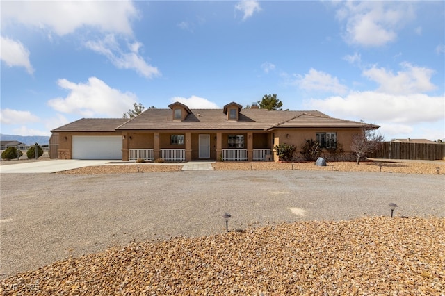 ranch-style home featuring a porch, fence, driveway, and stucco siding