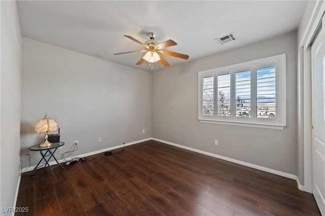 spare room featuring ceiling fan, wood finished floors, visible vents, and baseboards