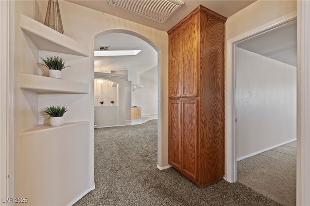 hall with arched walkways, visible vents, baseboards, and carpet floors