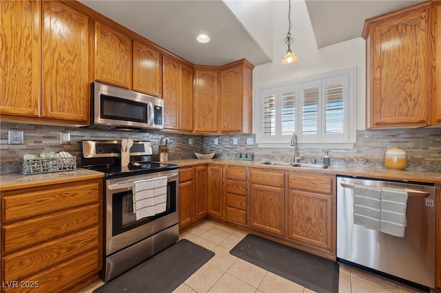 kitchen featuring light tile patterned flooring, a sink, appliances with stainless steel finishes, decorative light fixtures, and backsplash