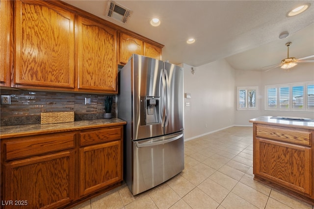 kitchen featuring light tile patterned floors, visible vents, stainless steel refrigerator with ice dispenser, brown cabinets, and backsplash