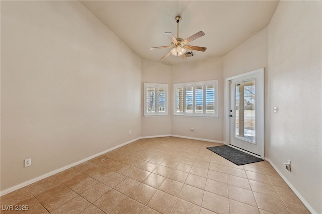 interior space featuring light tile patterned floors, visible vents, a ceiling fan, and baseboards