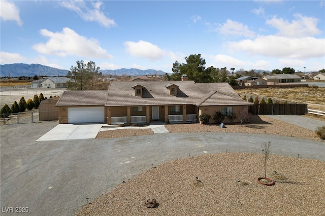 single story home featuring fence, driveway, an attached garage, covered porch, and a mountain view