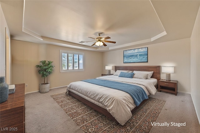 carpeted bedroom with a tray ceiling, baseboards, visible vents, and a ceiling fan