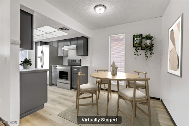 dining space with visible vents, baseboards, a textured ceiling, and light wood finished floors